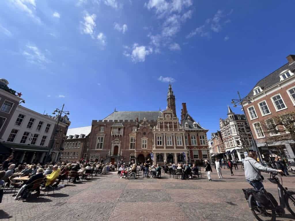 Haarlem square with people walking and others seating at restaurants